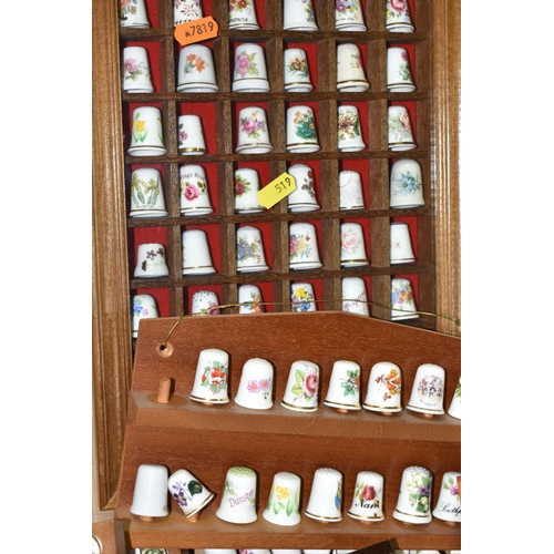 519 - A LARGE COLLECTION OF PORCELAIN THIMBLES, to include fourteen wooden thimble display stands and over... 