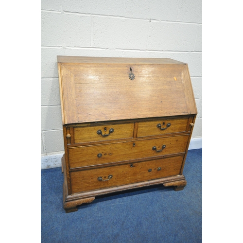 1200 - A GEORGIAN OAK BUREAU, the fall front door enclosing a fitted interior and green baize, above two sh... 