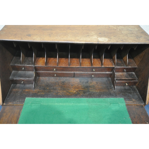 1200 - A GEORGIAN OAK BUREAU, the fall front door enclosing a fitted interior and green baize, above two sh... 