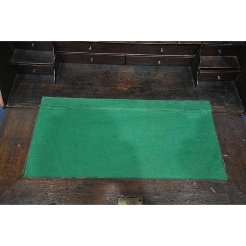 1200 - A GEORGIAN OAK BUREAU, the fall front door enclosing a fitted interior and green baize, above two sh... 