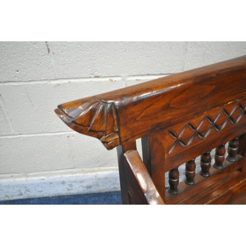 1211 - AN ANGLO INDIAN COLONIAL STYLE HARDWOOD CHILDS BENCH, carved with geometric designs, scrolled armres... 