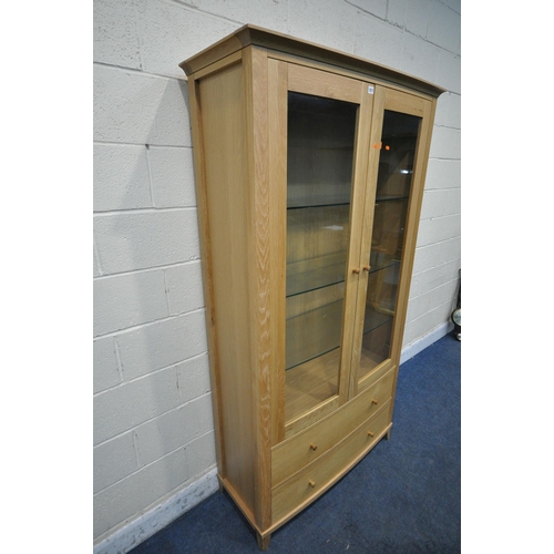 1217 - A SOLID LIGHT OAK BOW FRONT BOOKCASE, the double glazed doors enclosing three glass shelves, above t... 