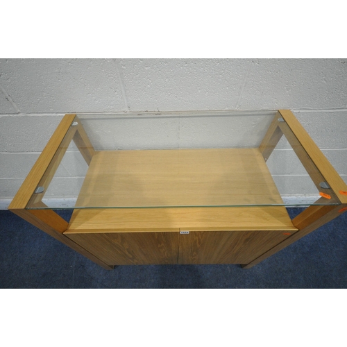 1224 - A SOLID LIGHT OAK SIDE TABLE, with a glass top, above two cupboard doors, width 90cm x depth 42cm x ... 