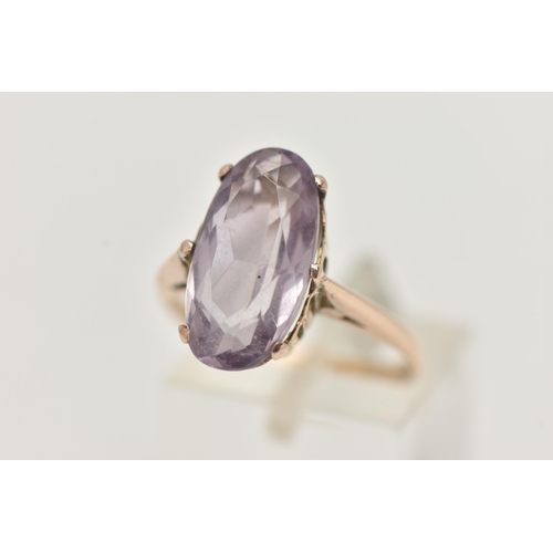 30 - AN AMETHYST RING, the large oval amethyst in a six claw setting, to the plain tapered band, unmarked... 