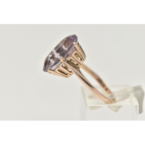 30 - AN AMETHYST RING, the large oval amethyst in a six claw setting, to the plain tapered band, unmarked... 