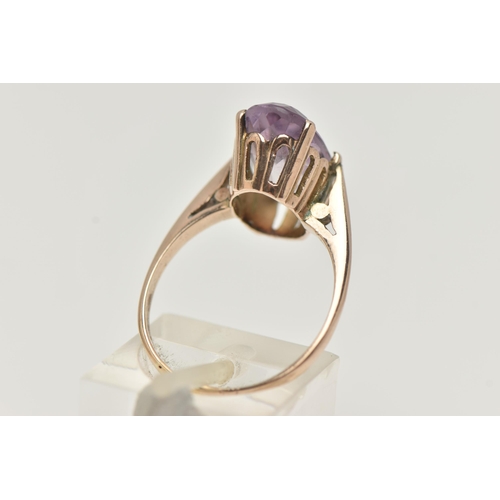 30 - AN AMETHYST RING, the large oval amethyst in a six claw setting, to the plain tapered band, unmarked... 