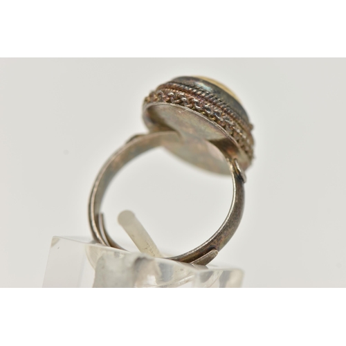 62 - A WHITE METAL RING, of an oval form, set with a cabcohon with bird detail, on a hinged cover, fine r... 