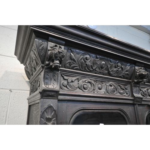 1198 - A LATE 19TH / EARLY 20TH CENTURY CARVED OAK GLAZED BOOKCASE, depicting lions masks and other detail,... 