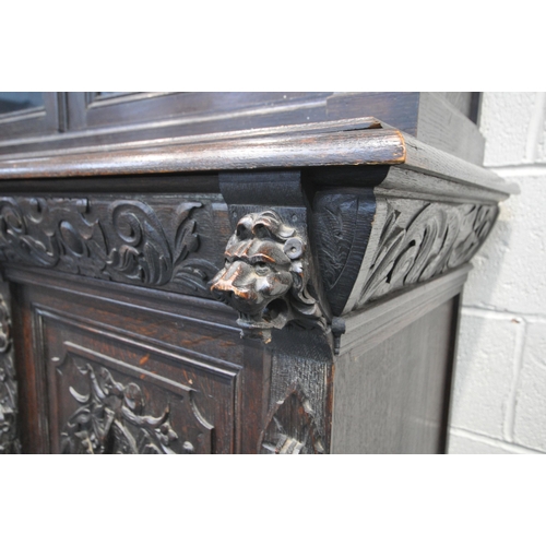 1198 - A LATE 19TH / EARLY 20TH CENTURY CARVED OAK GLAZED BOOKCASE, depicting lions masks and other detail,... 