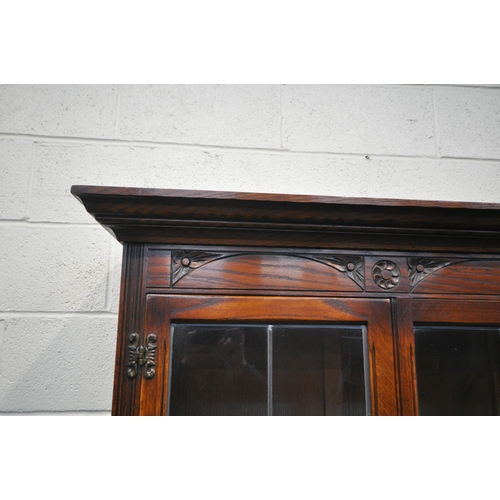 1252 - A 20TH CENTURY OLD CHARM OAK BOOKCASE, the top with double lead glazed doors, enclosing three glass ... 