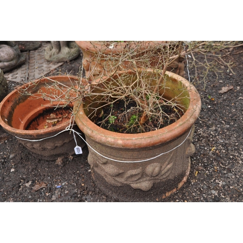 1028 - THREE TERRACOTTA PLANT POTS with embossed detailing to external edges the largest being 52cm in diam... 