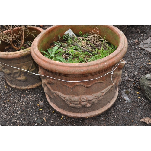 1028 - THREE TERRACOTTA PLANT POTS with embossed detailing to external edges the largest being 52cm in diam... 