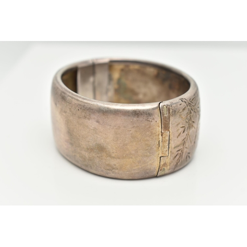 21 - A WHITE METAL HINGED BANGLE, wide bangle engraved with an oriental design, fitted with a push button... 