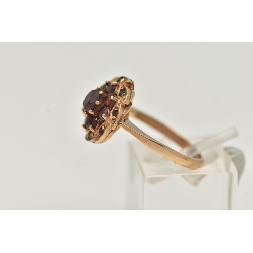 42 - A 9CT GOLD GARNET CLUSTER RING, designed as a circular garnet cluster, with leaf shape surround set ... 