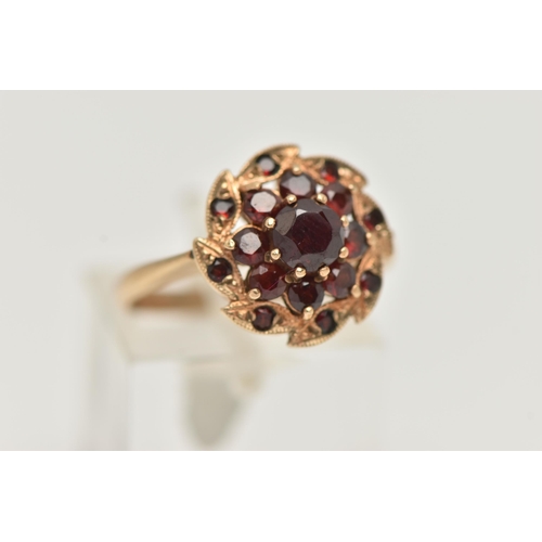 42 - A 9CT GOLD GARNET CLUSTER RING, designed as a circular garnet cluster, with leaf shape surround set ... 