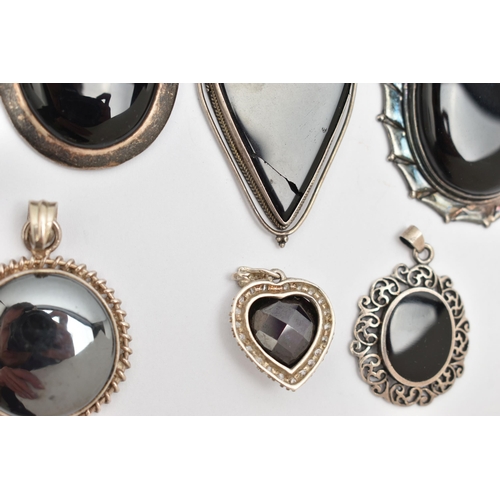 75 - SEVEN SILVER AND WHITE METAL PENDANTS, most set with onyx, also a circular hematite pendant, a heart... 