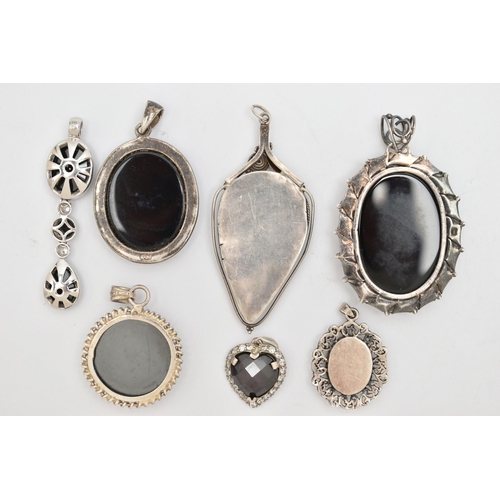 75 - SEVEN SILVER AND WHITE METAL PENDANTS, most set with onyx, also a circular hematite pendant, a heart... 