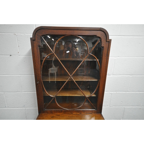 1213 - A 20TH CENTURY OAK CABINET, the single glazed door enclosing three adjustable shelves, above a singl... 