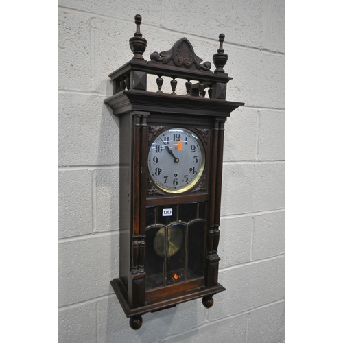 1303 - AN EARLY 20TH CENTURY WALL CLOCK, with finals and spindles above a full length door enclosing a silv... 