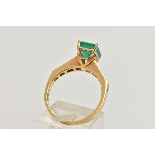 23 - A YELLOW METAL EMERALD AND DIAMOND RING, centering on an emerald cut emerald, measuring approximatel... 