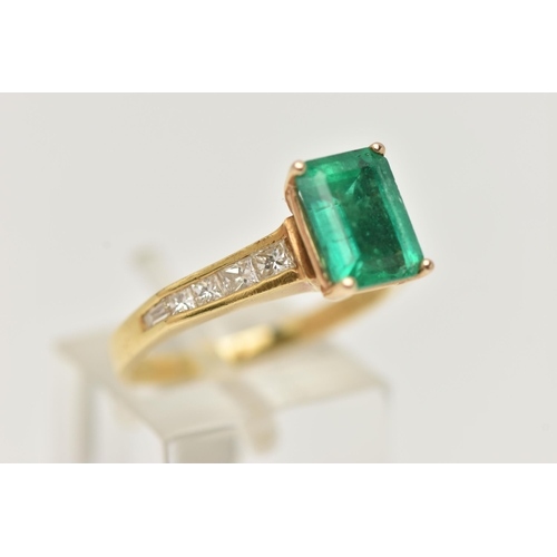 23 - A YELLOW METAL EMERALD AND DIAMOND RING, centering on an emerald cut emerald, measuring approximatel... 