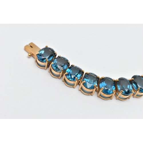 33 - A 9CT YELLOW GOLD TOPAZ BRACELET, designed as a series of approximately twenty-three oval blue topaz... 