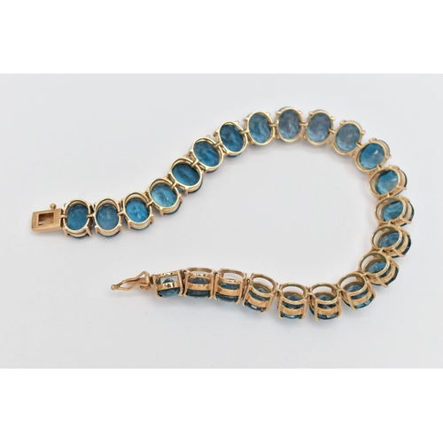 33 - A 9CT YELLOW GOLD TOPAZ BRACELET, designed as a series of approximately twenty-three oval blue topaz... 