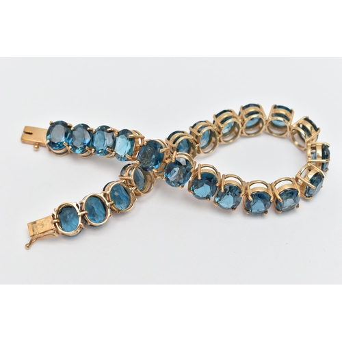 33 - A 9CT YELLOW GOLD TOPAZ BRACELET, designed as a series of approximately twenty-three oval blue topaz... 