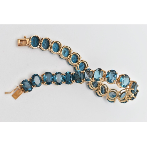 33 - A 9CT YELLOW GOLD TOPAZ BRACELET, designed as a series of approximately twenty-three oval blue topaz... 