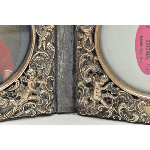 97 - A DOUBLE PHOTO FRAME, white metal lined frame, with  embossed foliate pattern with cherubs, folding ... 