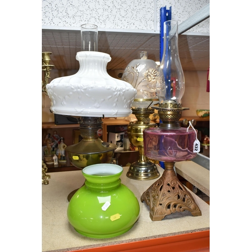 432 - THREE OIL LAMPS AND SHADES, comprising a lamp with a pierced cast iron base and cranberry glass oil ... 