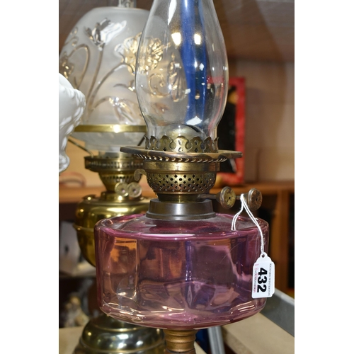 432 - THREE OIL LAMPS AND SHADES, comprising a lamp with a pierced cast iron base and cranberry glass oil ... 