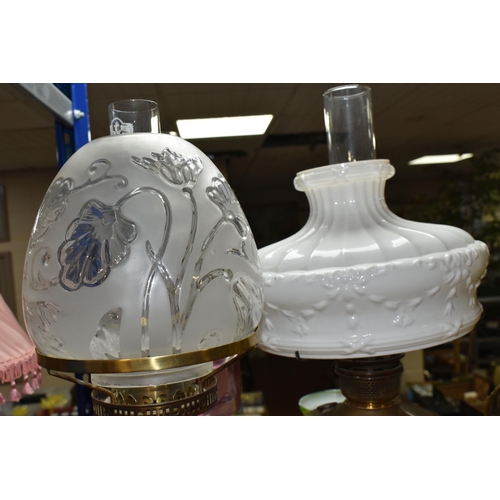 432 - THREE OIL LAMPS AND SHADES, comprising a lamp with a pierced cast iron base and cranberry glass oil ... 