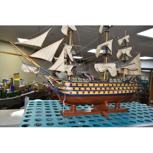 535 - A MODEL OF HMS VICTORY, a wooden ship with cloth sails, supported on a wooden stand with plaque, app... 