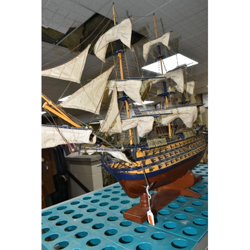 535 - A MODEL OF HMS VICTORY, a wooden ship with cloth sails, supported on a wooden stand with plaque, app... 