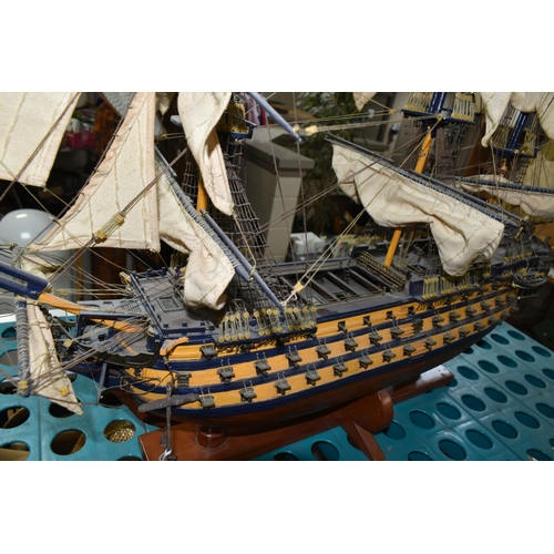 535 - A MODEL OF HMS VICTORY, a wooden ship with cloth sails, supported on a wooden stand with plaque, app... 