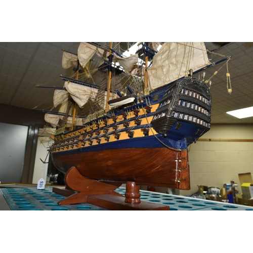 535 - A MODEL OF HMS VICTORY, a wooden ship with cloth sails, supported on a wooden stand with plaque, app... 