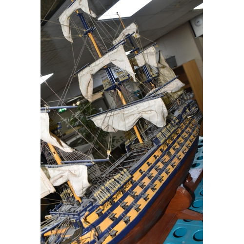 535 - A MODEL OF HMS VICTORY, a wooden ship with cloth sails, supported on a wooden stand with plaque, app... 