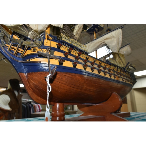 535 - A MODEL OF HMS VICTORY, a wooden ship with cloth sails, supported on a wooden stand with plaque, app... 