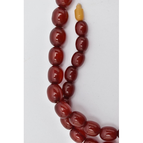 72 - A GRADUATED CHERRY AMBER, BAKELITE BEAD NECKLACE, graduated oval beads, smallest measuring approxima... 