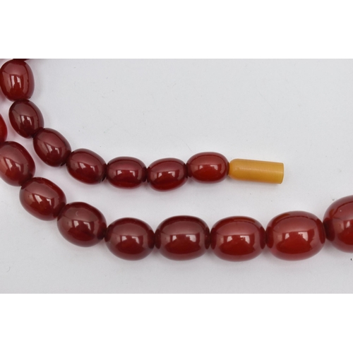 72 - A GRADUATED CHERRY AMBER, BAKELITE BEAD NECKLACE, graduated oval beads, smallest measuring approxima... 