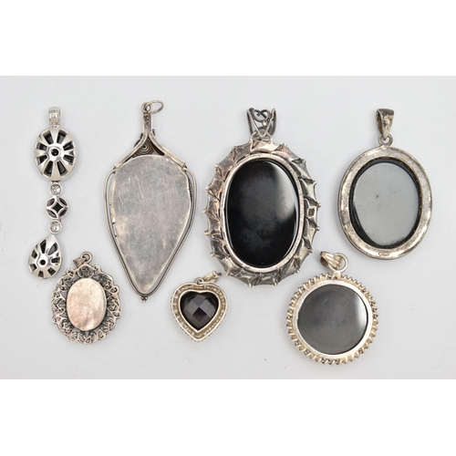 152 - SEVEN SILVER AND WHITE METAL PENDANTS, most set with onyx, also a circular hematite pendant, a heart... 