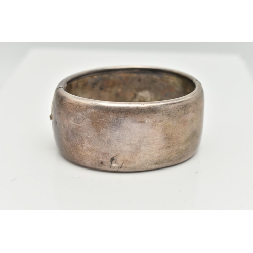 154 - A WHITE METAL HINGED BANGLE, wide bangle engraved with an oriental design, fitted with a push button... 