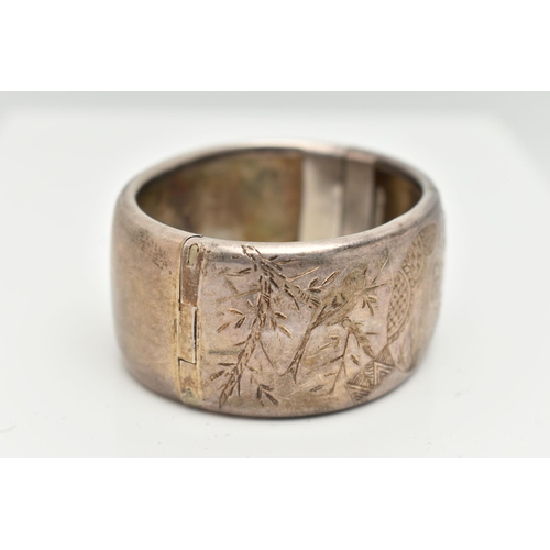 154 - A WHITE METAL HINGED BANGLE, wide bangle engraved with an oriental design, fitted with a push button... 