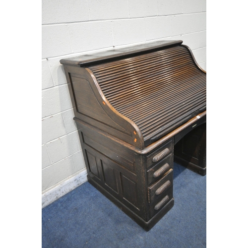 1329 - AN EARLY 20TH CENTURY OAK ROLL TOP DESK, enclosing a fitted interior, on two pedestals, each with fo... 