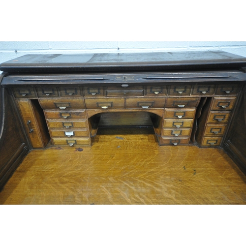 1329 - AN EARLY 20TH CENTURY OAK ROLL TOP DESK, enclosing a fitted interior, on two pedestals, each with fo... 