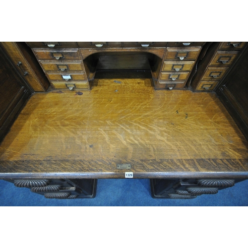 1329 - AN EARLY 20TH CENTURY OAK ROLL TOP DESK, enclosing a fitted interior, on two pedestals, each with fo... 