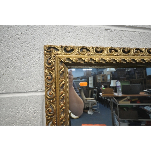 1352 - A RECTANGULAR GILT RESIN BEVELLED EDGE WALL MIRROR, with foliate details,108cm x 77cm, along with an... 