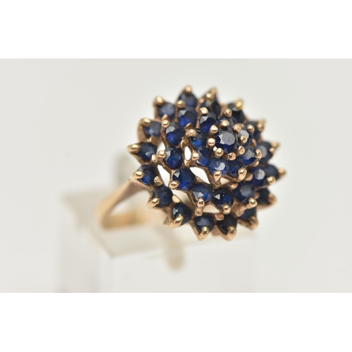 43 - A SAPPHIRE CLUSTER RING, designed as a tiered cluster of circular sapphires in claw settings, stampe... 