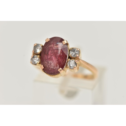 67 - A YELLOW METAL FIVE STONE RING, centering on an oval cut heavily fracture filled red corundum, in a ... 